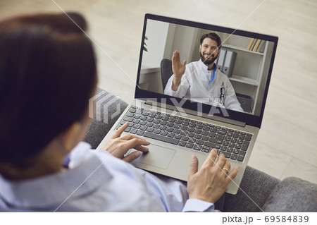 Smiling confident man doctor greeting man patient with hand online from laptop 69584839