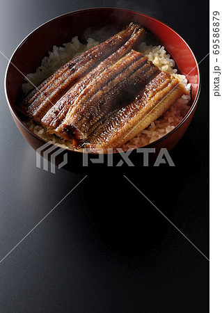 1匹分の鰻の蒲焼きが乗った熱々な鰻丼(黒背景) 1匹分の鰻の蒲焼きが乗った熱々な鰻丼(黒背景) 69586879
