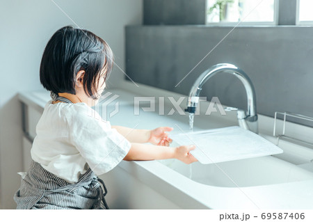 綺麗なキッチンで女の子がまな板を洗っている　kitchen girl wash 69587406