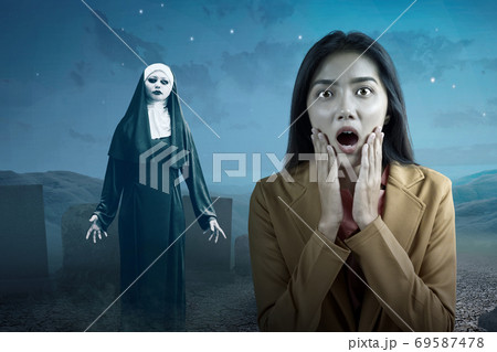 Asian businesswoman scared looking at frightening devil nun Asian businesswoman scared looking at frightening devil nun 69587478