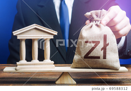 Businessman puts a polish zloty money bag on scales opposite to government state building. Lending to government projects. Payment of taxes and fees. Budgeting. Financing Social programs. Bank deposit 69588312
