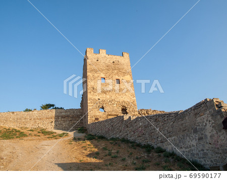 Stone tower of an ancient fortress with adjoining rocky walls 69590177
