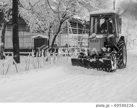 Tractor removing snow from the footpaths in the city park after snowfall Tractor removing snow from the footpaths in the city park after snowfall 69590226