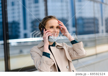 A young businesswoman wearing a health mask and talking on the phone in the city 69592324
