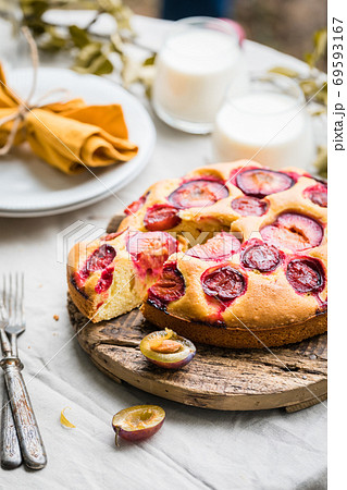 Close up of traditional homemade plum cake or pie with summer table setting Close up of traditional homemade plum cake or pie with summer table setting 69593167