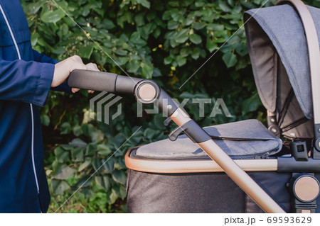 Mom walking with grey stroller. Nature background. 69593629