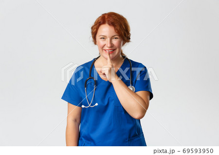 Medicine, healthcare and coronavirus concept. Happy smiling female doctor, nurse asking keep secret, shushing, press finger to lips and hush, tell be quiet, prepared surprise, grey background Medicine, healthcare and coronavirus concept. Happy smiling female doctor, nurse asking keep secret, shushing, press finger to lips and hush, tell be quiet, prepared surprise, grey background 69593950