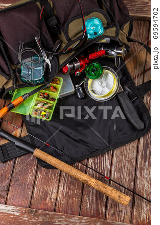 Different fishing tacles with rod and reels on wooden brown background. 69594702