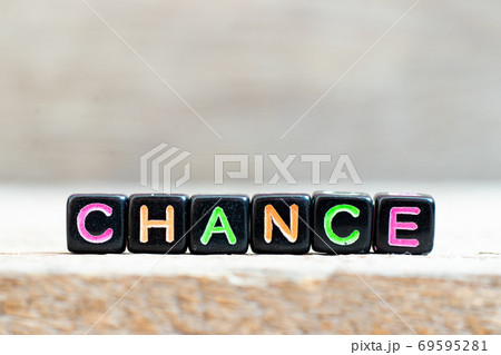 Black bead with color letter in word chance on wood background 69595281