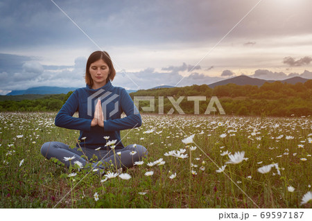 A young woman doing yoga in the field. 69597187