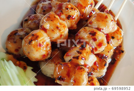 Grilled meat balls topping dipping with spicy hot sauce decorated with chili peppers Thai food appetizer and slide organic fresh cucumber on white flat plate, food menu advertising backgrounds 69598952