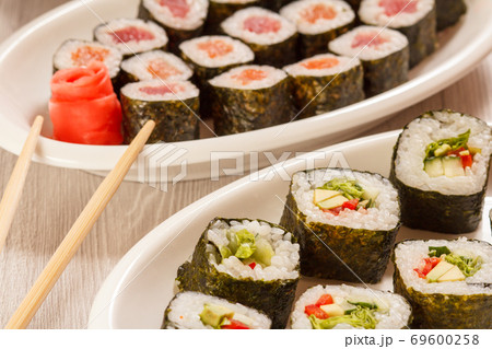 Sushi rolls with rice, vegetable and seafood on plates with wooden chopsticks 69600258