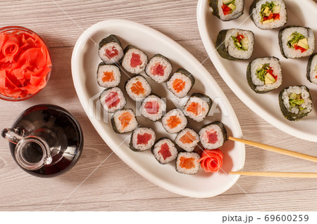 Sushi rolls with rice, vegetable and seafood on plate with bottle of soy sauce 69600259