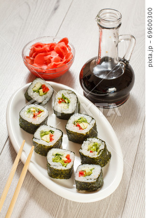 Sushi rolls with rice on plate, chopsticks and glass bottle with soy sauce 69600300