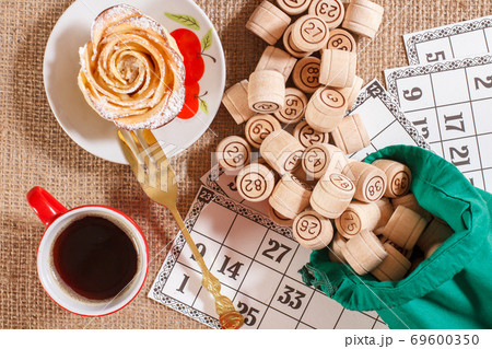 Board game lotto. Wooden lotto barrels in bag and game cards with cup of coffee Board game lotto. Wooden lotto barrels in bag and game cards with cup of coffee 69600350