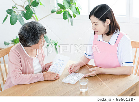 薬ケースの説明をする介護士 69601387