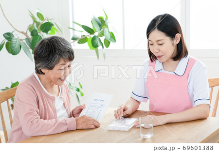 薬ケースの説明をする介護士 69601388