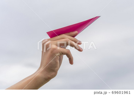 Child's hand launches a red paper airplane on a background of cloudy sky. The concept of imagination about setting life goals 69601961