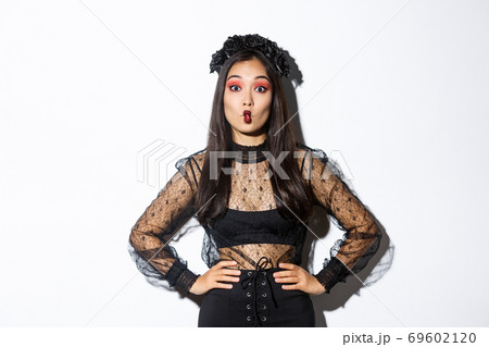 Portrait of silly attractive asian woman fooling around, showing funny faces at camera while wearing halloween costume, standing over white background Portrait of silly attractive asian woman fooling around, showing funny faces at camera while wearing halloween costume, standing over white background 69602120