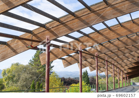 A disassembled wooden roof of the cottage against a blue cloudy sky and trees with mountain peaks in the distance. Preparation and conduct of reconstruction and repair of the building 69602157