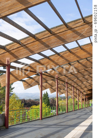 A disassembled wooden roof of the cottage against a blue cloudy sky and trees with mountain peaks in the distance. Preparation and conduct of reconstruction and repair of the building. Vertical view 69602158