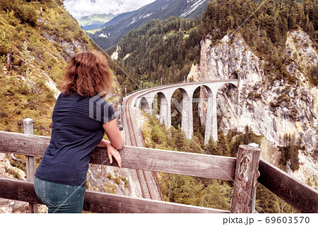 Female tourist looks at Landwasser Viaduct in Switzerland 69603570