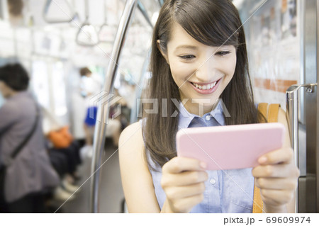 電車でスマホを見る女性 69609974