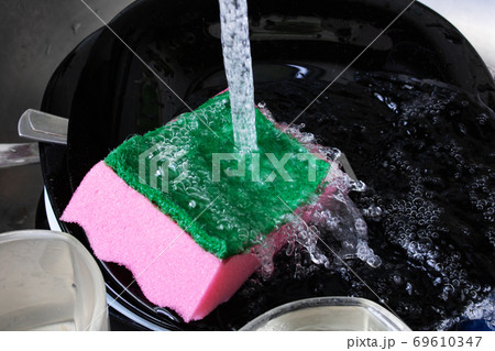 Dishes and sponge underwater in the sink 69610347