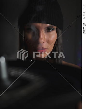 Brunette smoking hookah in dark room 69613392