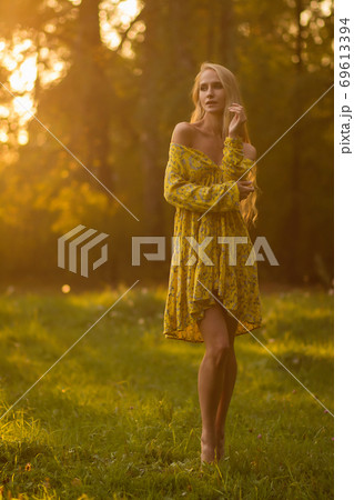 Blond woman resting in forest at sunset Blond woman resting in forest at sunset 69613394