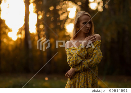 Blond woman resting in forest at sunset Blond woman resting in forest at sunset 69614691