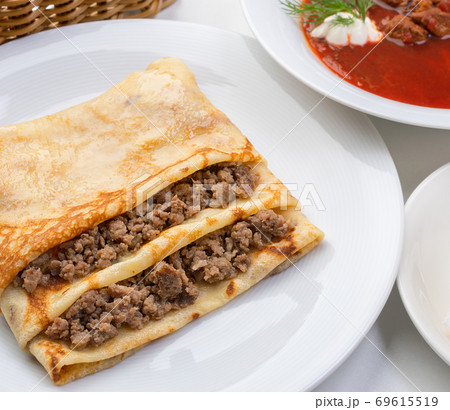 Pancake stuffed with meat and borsch with greenery 69615519