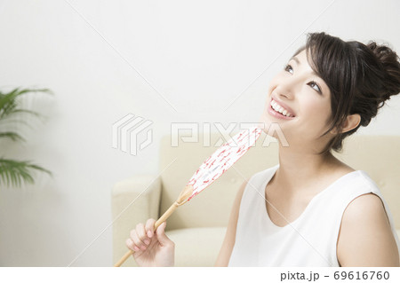 うちわで扇ぐ女性 69616760