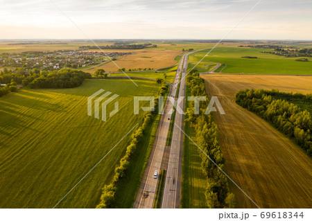 Top view of the road with cars and fields around the road.Fields and trees near the highway with moving cars.Belarus Top view of the road with cars and fields around the road.Fields and trees near the highway with moving cars.Belarus 69618344