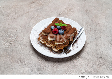portion of Classic tiramisu dessert with raspberries and blueberries on grey concrete background portion of Classic tiramisu dessert with raspberries and blueberries on grey concrete background 69618570