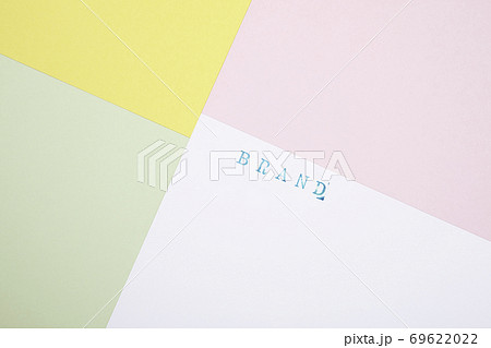 斜めに配置した4色の紙とbrandスタンプ文字 ピンクと黄緑色 白背景の写真素材