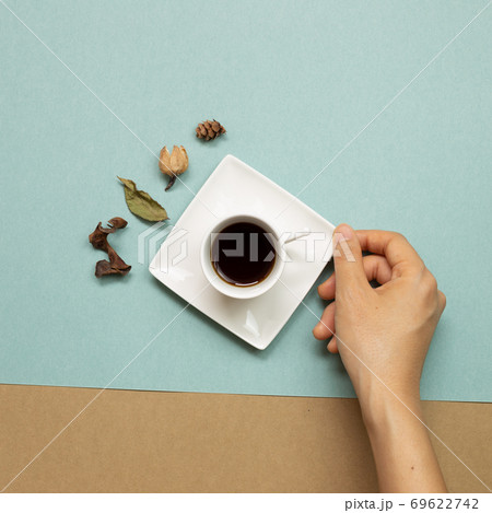 Hand holding cup of coffee with autumn dry leaves on green and brown background. flat lay, top view 69622742