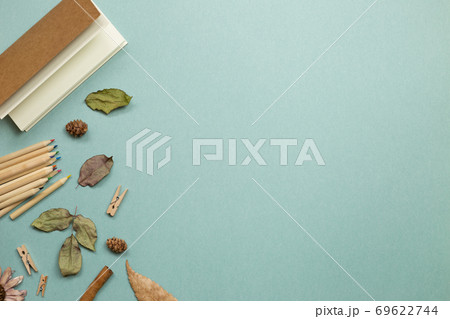 Autumn concept. Notebook and wooden colored pencils with dry leaves on green background. flat lay, top view, copy space. Work and study place Autumn concept. Notebook and wooden colored pencils with dry leaves on green background. flat lay, top view, copy space. Work and study place 69622744