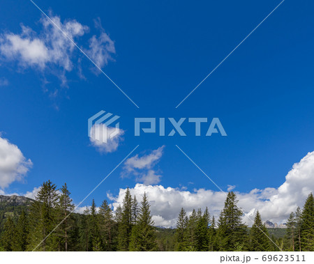 Beautiful blue sky with textured clouds and mountain peaks along the bottom of the image 69623511