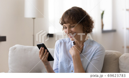 Happy Caucasian woman smile reading message on smartphone Happy Caucasian woman smile reading message on smartphone 69623783