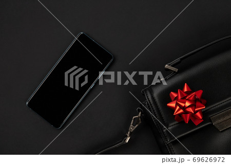 Creative flat lay top view composition with bag, smartphone and bow Creative flat lay top view composition with bag, smartphone and bow 69626972
