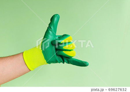 Male hand in a glove for working in the garden, vegetable garden. Hand gesture - Call me. Copy space 69627632