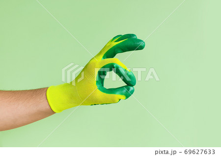 Male hand in a glove for working in the garden, vegetable garden. Worker showing gesture - ok sign. Male hand in a glove for working in the garden, vegetable garden. Worker showing gesture - ok sign. 69627633