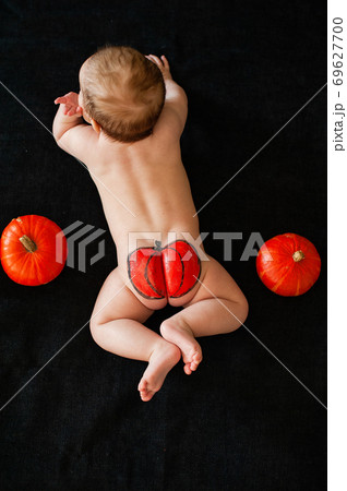 baby ass with painted pumpkin on black background baby ass with painted pumpkin on black background 69627700