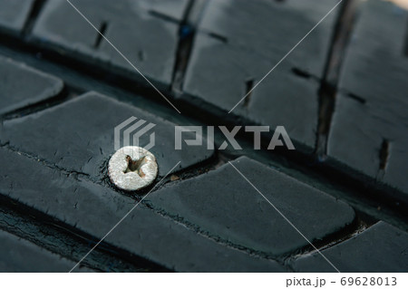 Close up metal screws nails embroidered in tires 69628013