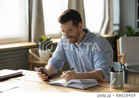 Smiling man use smartphone making notes planning Smiling man use smartphone making notes planning 69628409