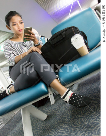 A young woman with mobile phone sitting in waiting room. Traveler waits for his transport connection 69628590