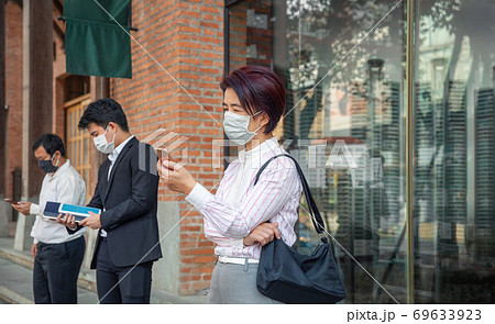 Asian people wearing mask and keep social distancing to avoid the spread of COVID-19 69633923