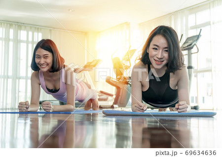 Attractive young cheerful asian woman wearing sportswear with push up arm Attractive young cheerful asian woman wearing sportswear with push up arm 69634636
