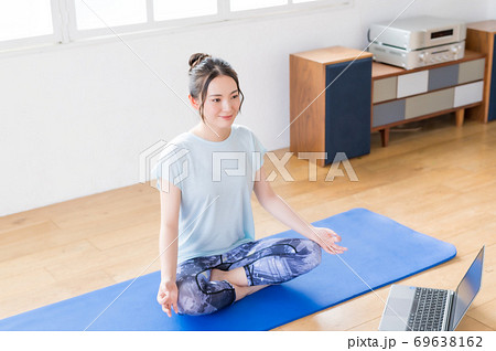 リビングでオンラインヨガする若い女性 69638162